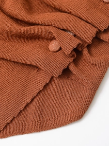 Macro detail of caramel brown ribbed knit fabric with matching fabric-covered button