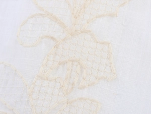 Detailed macro view of white floral lace and intricate hollow embroidery on fabric