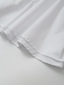 Detailed close-up of white high-waist skirt hem with double-needle sewing craftsmanship