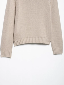 Detailed macro view of the beige knitted cardigan showing soft ribbed hem and cuff texture