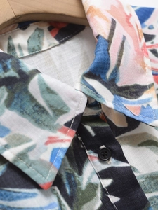Détail du tissu à imprimé tropical et des boutons en résine sur une robe à col en V