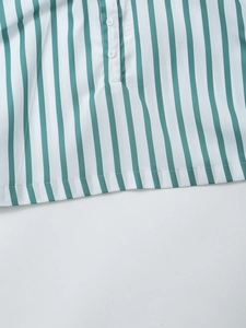 Détail d'une chemise en popeline à rayures vertes et blanches avec deux boutons blancs