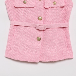 Detail of pink tweed vest showing woven texture, gold buttons and belted waist detail