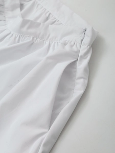 Detail view of white pleated skirt featuring a seamless hidden zipper and side pocket