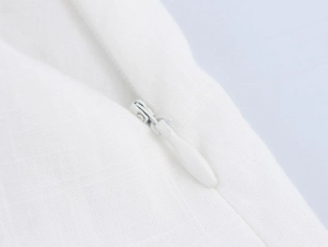 Macro view of white lace patchwork dress featuring hidden zipper and weave texture