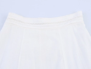 Detail of white cotton skirt waist featuring intricate hollow eyelet embroidery and texture