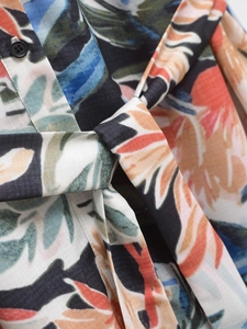 Détail de la robe à imprimé tropical avec bouton en résine et ceinture à nouer à la taille