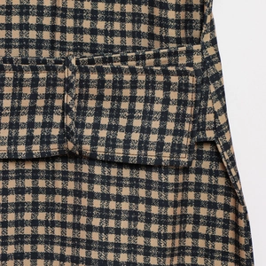 Detailed close-up of the black and khaki plaid fabric with stitched pocket flap detail