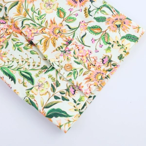 Detail shot of a floral summer dress cuff featuring pink flowers and a wooden button