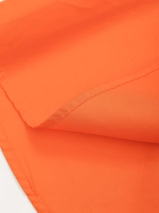 Gros plan sur le tissu orange vif montrant les détails de couture double de qualité