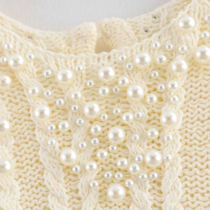 Cream knit top with elegant pearl embellishments and classic cable knit texture