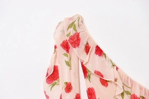 Detailed view of pink floral chiffon fabric with ruffled edges and red rose print