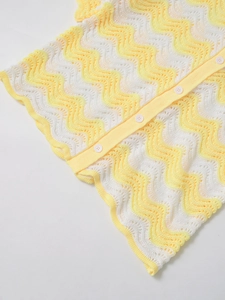 Close-up of yellow and white wavy knit texture with round buttons on women's top