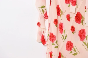 Detail of pink floral chiffon fabric featuring red roses and ruffle edge texture