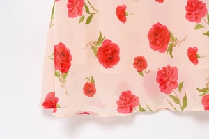 Detail of pink chiffon dress featuring red rose prints and delicate rolled hem finish