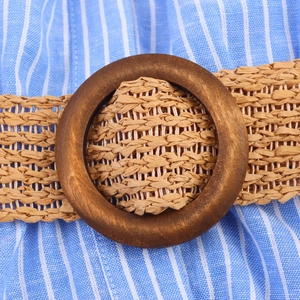 Detailed macro view of bohemian woven straw belt with a dark round wooden buckle