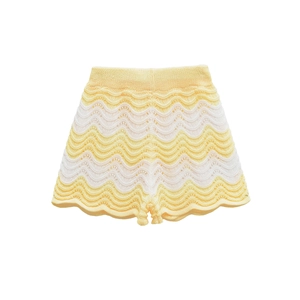 Detail of yellow and beige wavy knit shorts with elastic waist and scalloped edges
