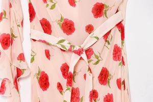 Detail of pink floral dress featuring rose prints, waist tie, and ruffled sleeve edges