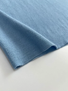 Dettaglio del tessuto a maglia fine azzurro che mostra la consistenza morbida e il bordo