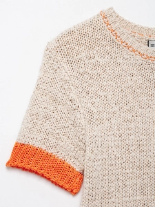 Close-up of beige chunky knit sweater with vibrant orange trim and round neckline details
