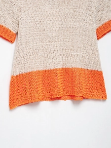 Detail of color-block knit sweater showing cream and orange chunky crochet texture