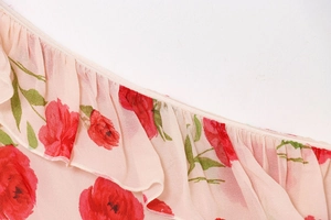 Detail view of pink floral print chiffon fabric with ruffled edges and fine stitching