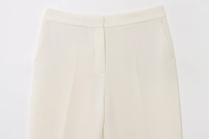 Detailed close-up of cream white suit trousers with waist pleats and side pockets