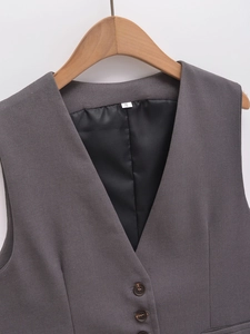 Détail du gilet gris foncé à col en V montrant la texture sergée et les boutons