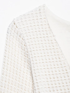 Detail of white crochet knit fabric showing intricate hollow mesh texture and inner lining