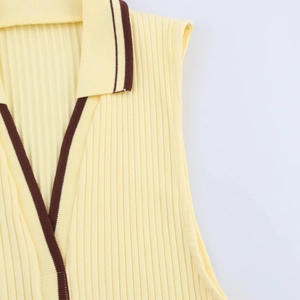 Detail of light yellow ribbed knit tank top with polo collar and brown contrast piping