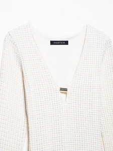Detail of white crochet knit midi dress showing deep V-neckline and silver metal hardware