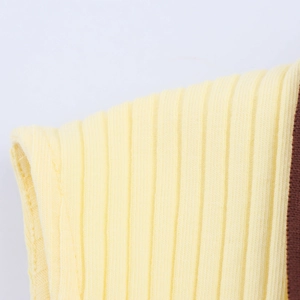 Close-up of yellow ribbed knit fabric showing brown contrast binding and fine textile texture