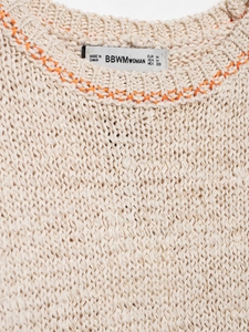 Close-up of knit sweater texture with orange hand-stitched detail on the neckline