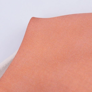 Détail du tissu texturé orange corail avec éclat satiné et doublure en maille blanche