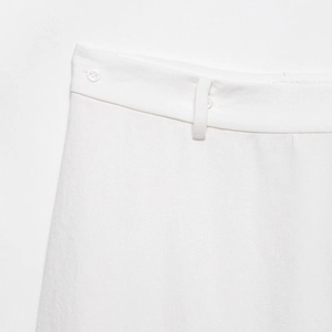 Close-up of white pleated dress waist featuring weave texture and translucent button