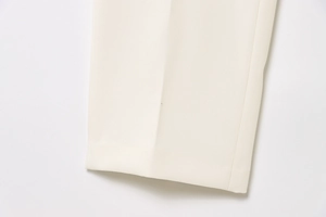 Detail of cream straight trousers with vertical ironed pleat and woven texture
