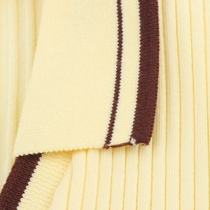 Macro detail of ribbed yellow knit polo top with brown contrast piping and neat stitching