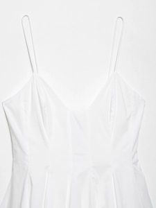 Détail d'une robe blanche à col en V avec fines bretelles et plis à la taille