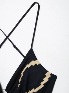 Detail of black summer dress with beige geometric pattern and thin adjustable metal ring straps