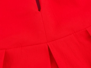 Vue détaillée du tissu plissé rouge avec des coutures soignées et une texture lisse