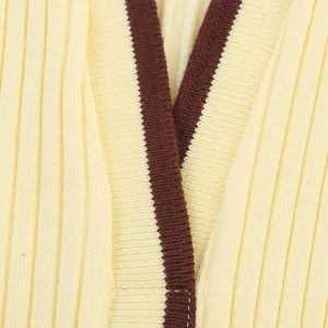 Detail of ribbed knit texture on cream sleeveless polo top with brown trim accents