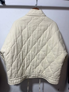 Detailed back view of cream onion-quilted jacket with drawstring hem and stand collar