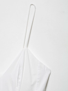 Gros plan sur les fines bretelles blanches et le tissu texturé de l'encolure de la robe