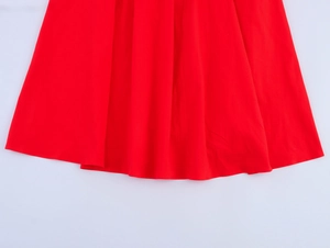 Vue détaillée de l'ourlet de la robe midi rouge fluide montrant la texture du tissu tissé