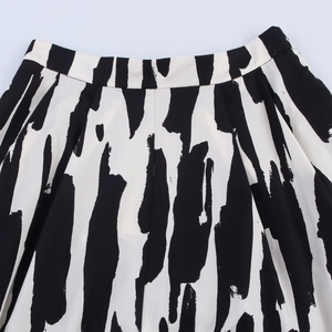 Detailed close-up of high-waist pleated skirt with abstract black and white brushstroke pattern