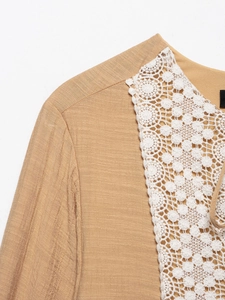 Detail view of khaki women's blouse featuring intricate white lace collar and textured fabric