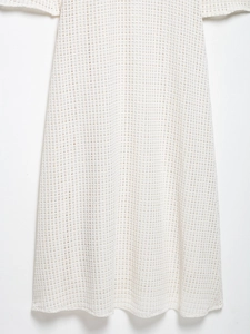 Detail of white midi crochet dress featuring intricate hollow-out mesh texture
