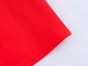 Détail de la texture du tissu rouge avec ourlet à double couture et finition soignée