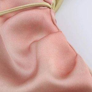 Détail de robe en satin rose montrant les coutures fines et la texture soyeuse
