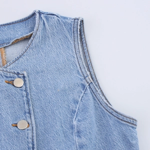 Détail de gilet en jean bleu clair avec boutons métalliques et bords effilochés